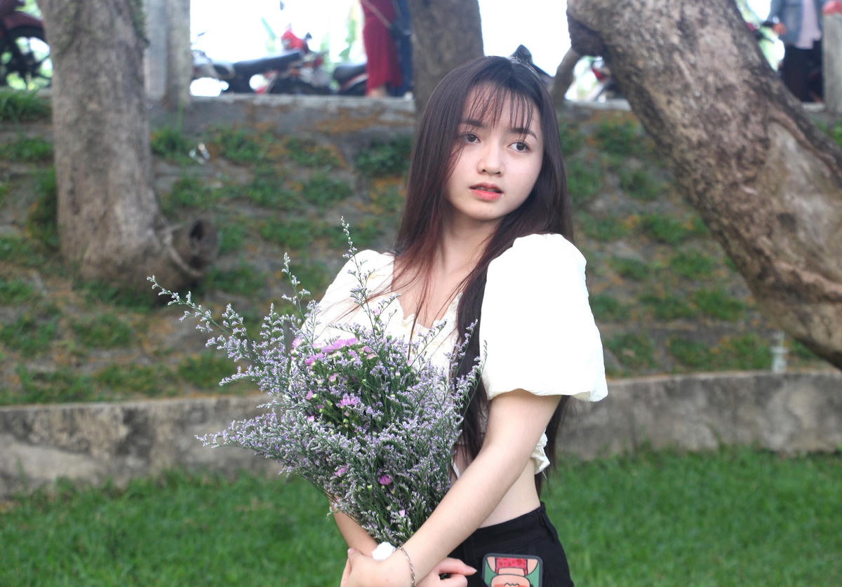 Cô gái trẻ tạo dáng cùng hoa để lưu lại khoảnh khắc đẹp.