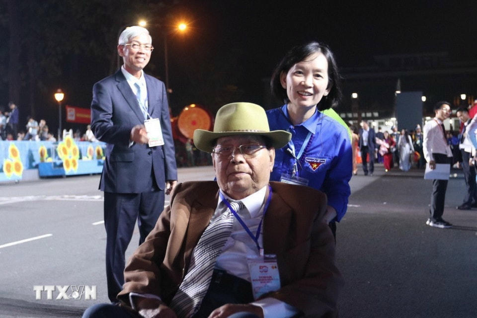 Một đại biểu cao tuổi được tình nguyện viên hỗ trợ vào vị trí. (Ảnh: TTXVN)