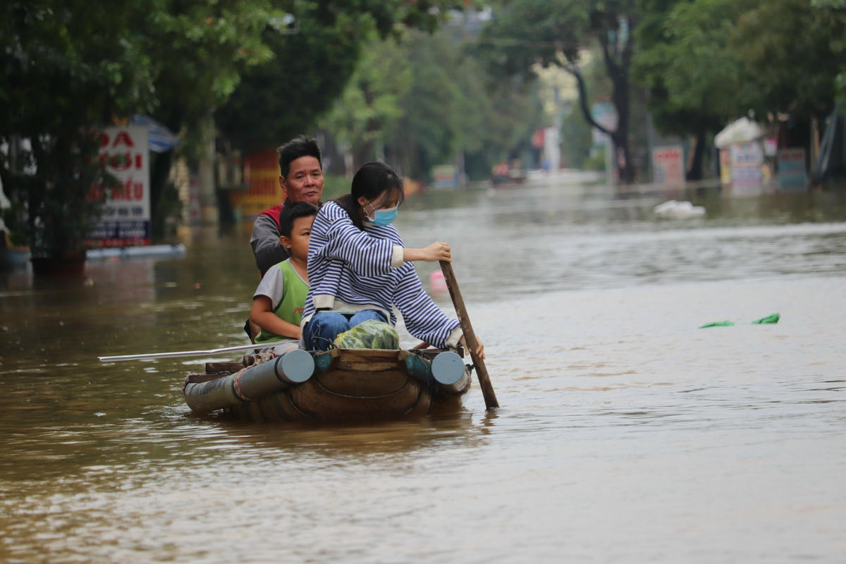 Nước lũ gây ngập nhiều tuyến đường buộc người dân phải dùng thuyền di chuyển.