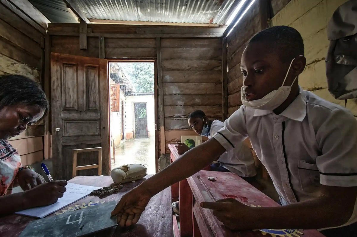 Juan Isaac (phía trước) và Gael học toán với Bilogo. La Fe là trung tâm giáo dục đầu tiên ở Guinea Xích Đạo mở cửa đón học sinh có nhu cầu giáo dục đặc biệt. Ảnh: Diego Menjibar Reynes.