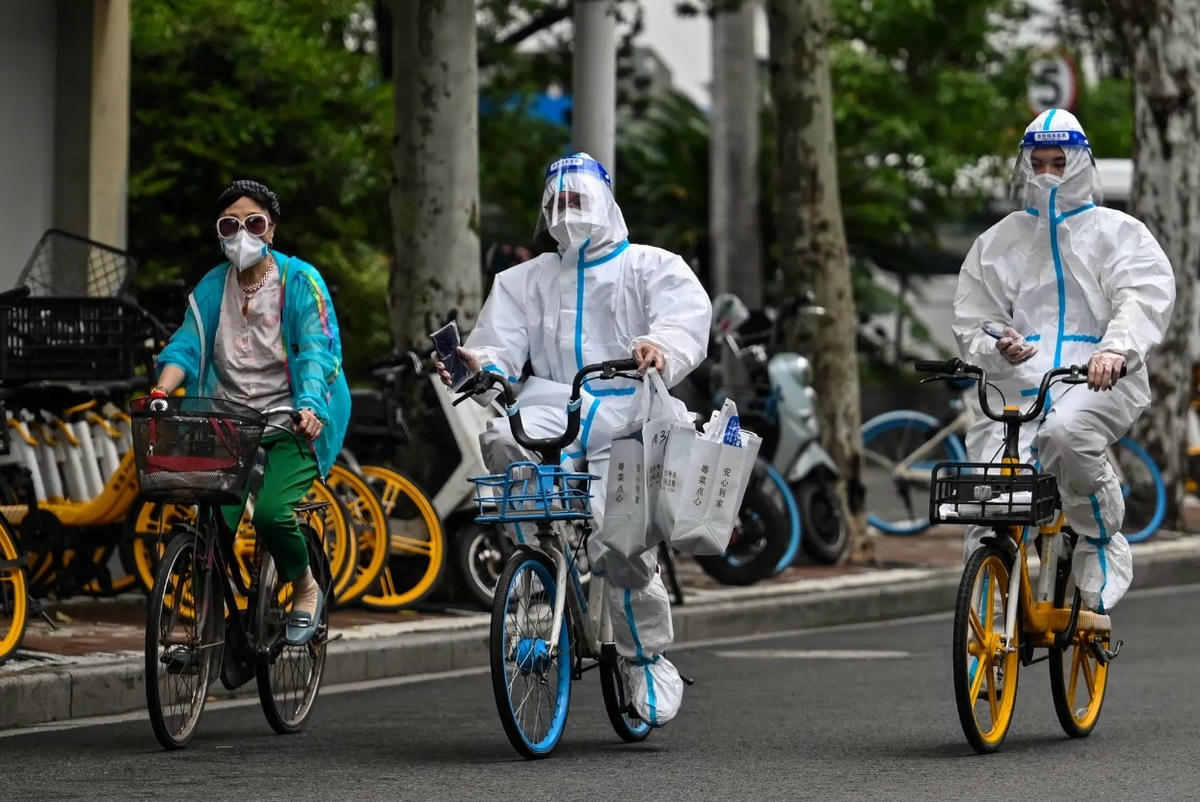 Công nhân mặc đồ bảo hộ đạp xe trên đường phố trong đợt giãn cách do đại dịch Covid-19 ở quận Jing'an. Ảnh: AFP.