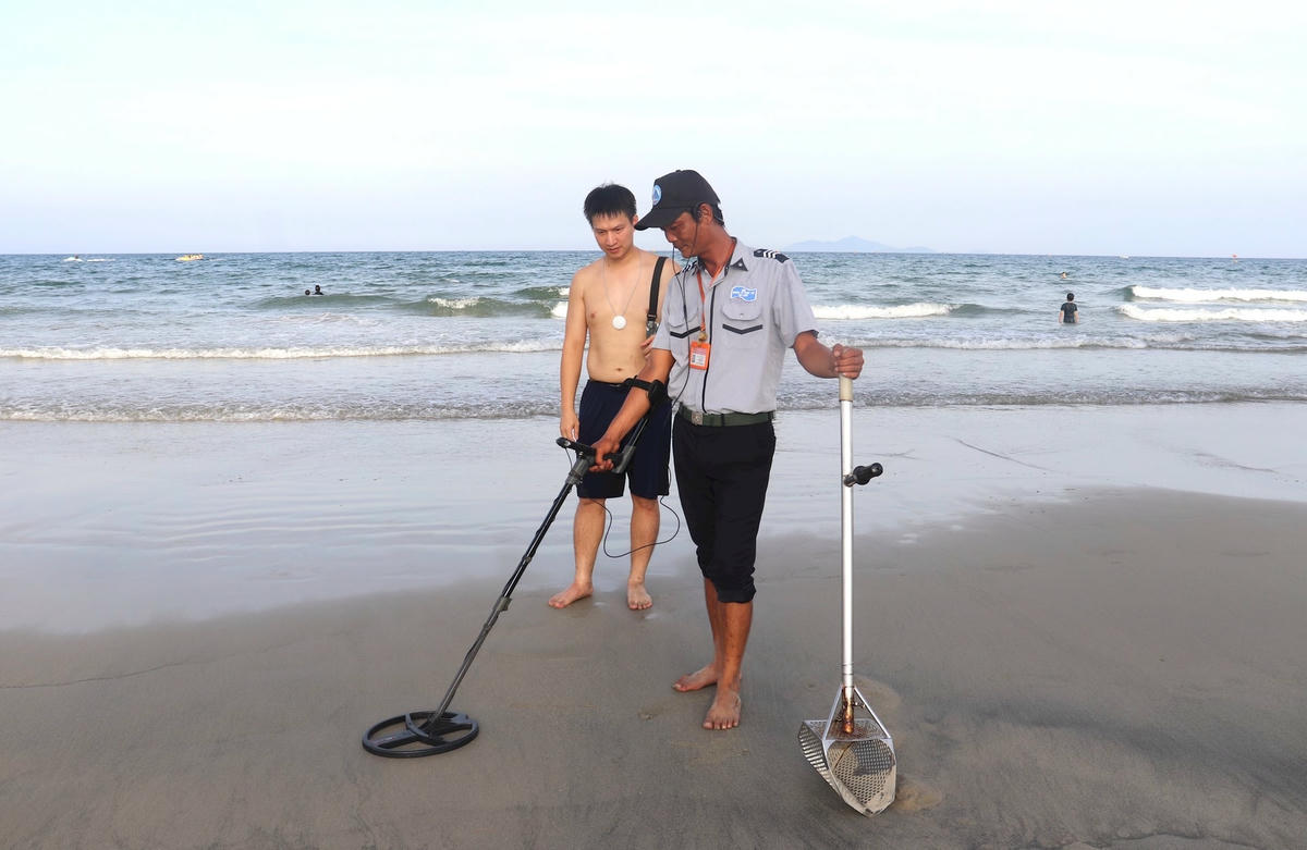 Anh Phan Thanh Trinh, nhân viên Đội quản lý trật tự du lịch biển, Ban Quản lý bán đảo Sơn Trà và các bãi biển du lịch Đà Nẵng dùng máy dò tìm đồ vật cho du khách. Ảnh