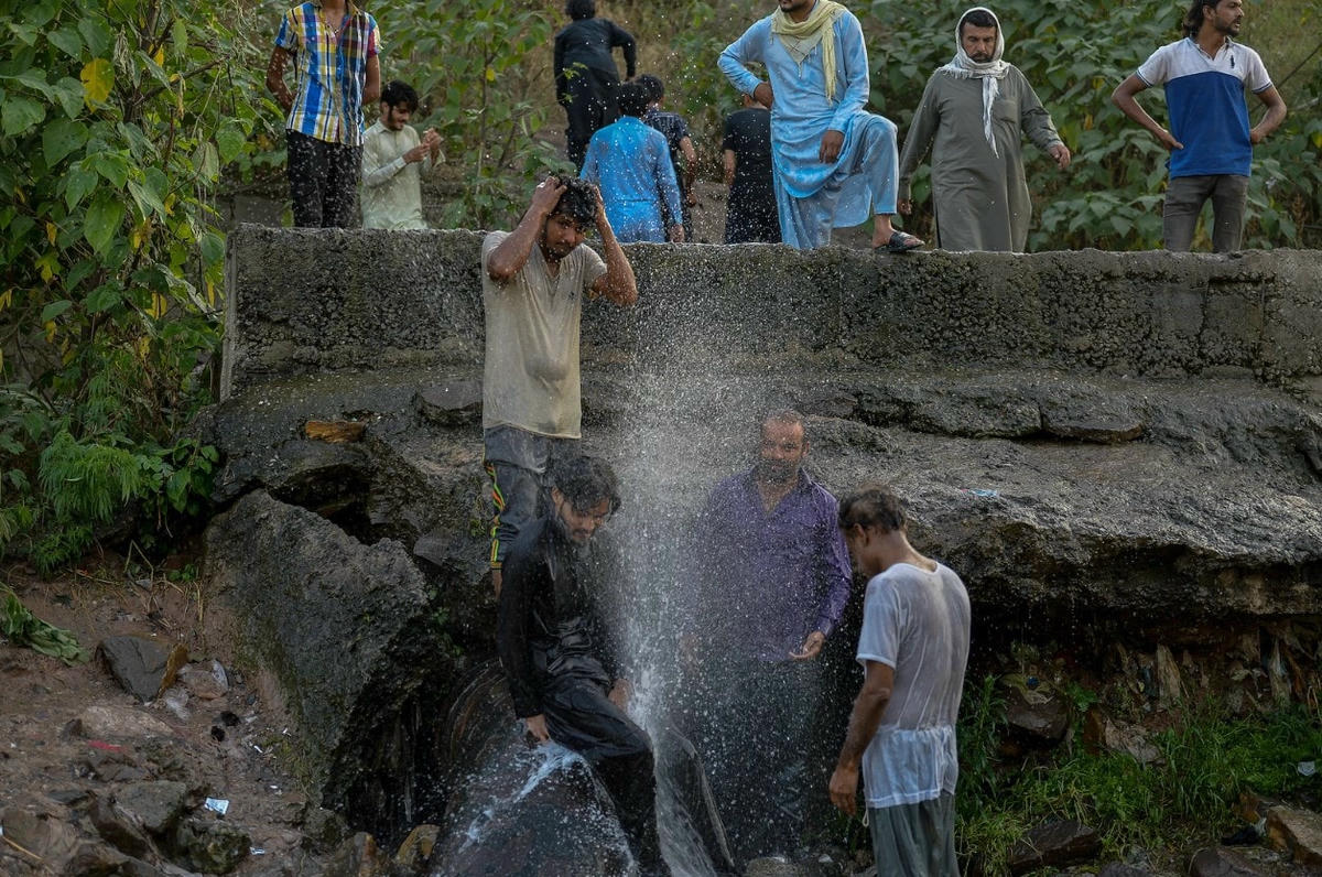 Người dân giải nhiệt bằng cách sử dụng nước rò rỉ từ một đường ống ở Islamabad, Pakistan. Ảnh: VICE.