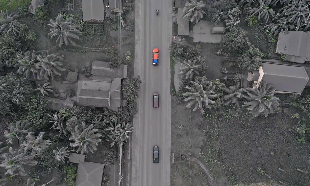 Các phương tiện chạy qua những ngôi nhà và thảm thực vật phủ đầy tro bụi ở thị trấn Juban sau khi núi lửa Bulusan phun trào. Ảnh: Getty Images.