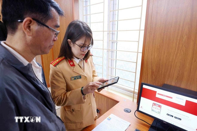 Cán bộ, chiến sỹ Đội Sát hạch, cấp giấy phép lái xe cơ giới đường bộ (Phòng Cảnh sát giao thông, Công an thành phố Hà Nội) hướng dẫn người dân đăng ký làm thủ tục cấp, đổi giấy phép lái xe trên Cổng dịch vụ công quốc gia và ứng dụng VNeID. (Ảnh: Phạm Kiên/TTXVN) ttxvn-giay-phep-lai-xe.jpg