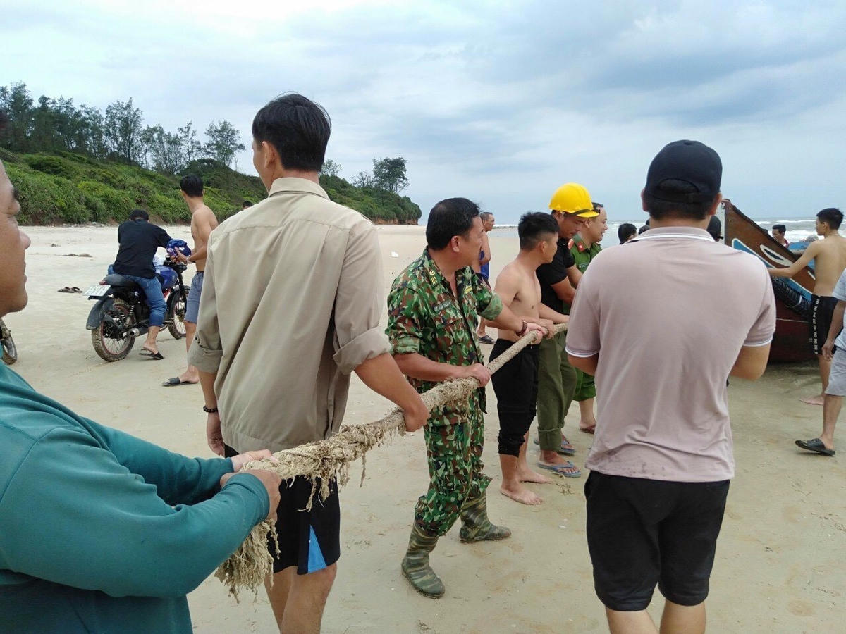 Lực lượng chức năng và người dân tiến hành trục vớt thuyền gặp nạn.