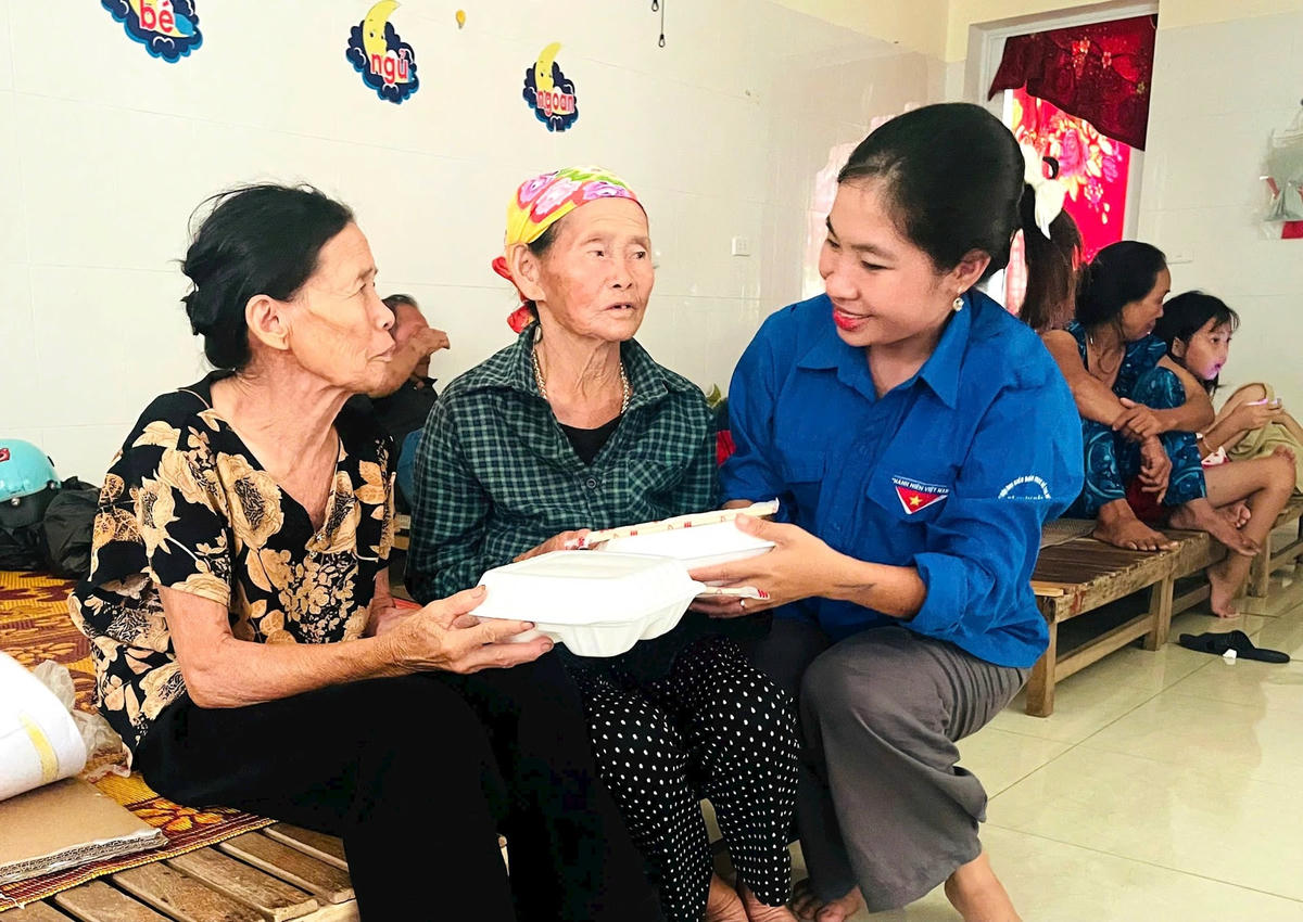 Bà Trần Thị Ngân (mặc áo hoa) xúc động nhận hộp cơm từ đoàn viên chi đoàn xã Đan Hải (Hà Tĩnh). Ảnh HN.