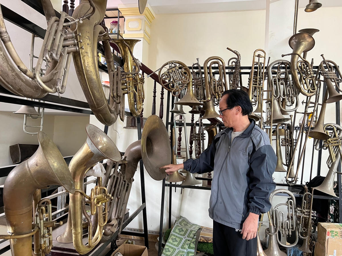 Ông Nguyễn Văn Đông bên những chiếc kèn đồng do mình chế tác.