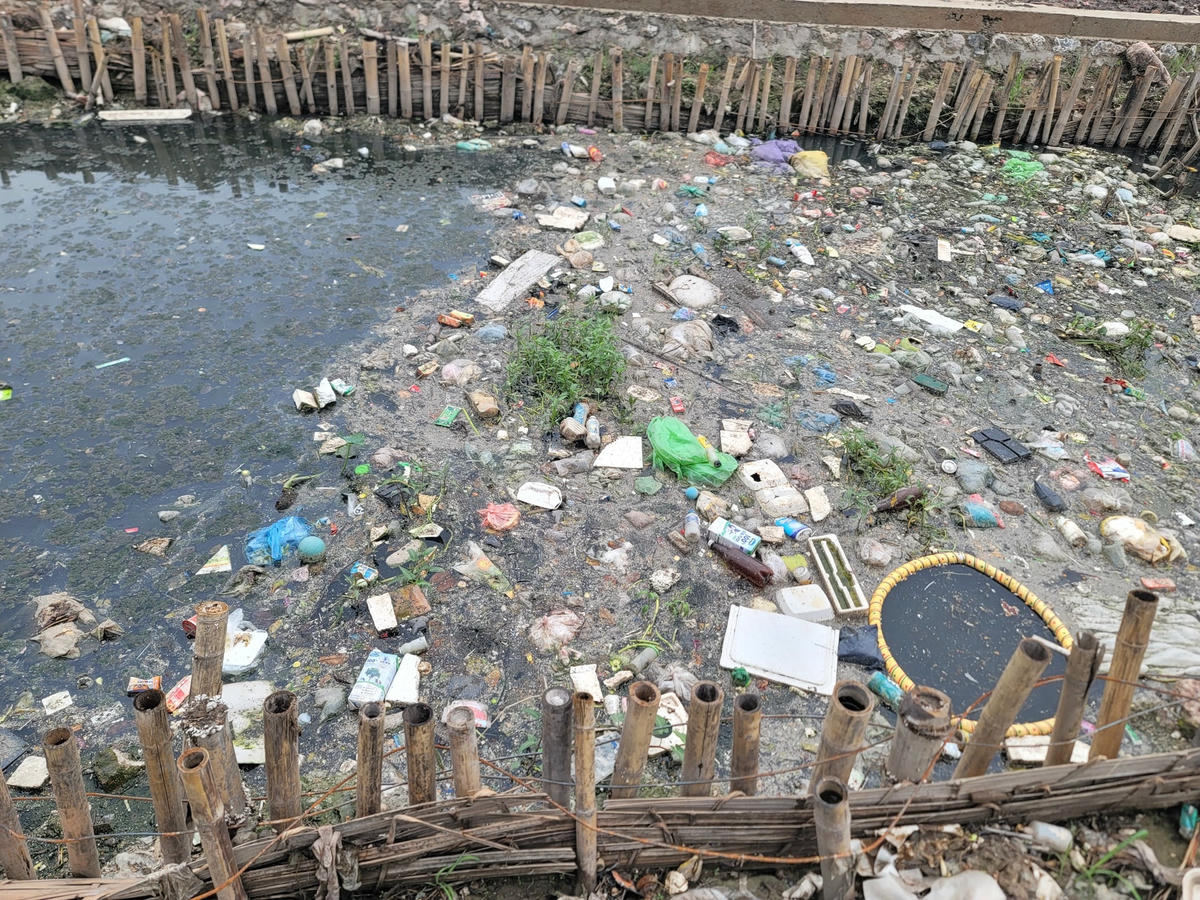 Rác phủ kín mặt sông, nước sông đen kịt, ô nhiễm, bốc mùi hôi thối.