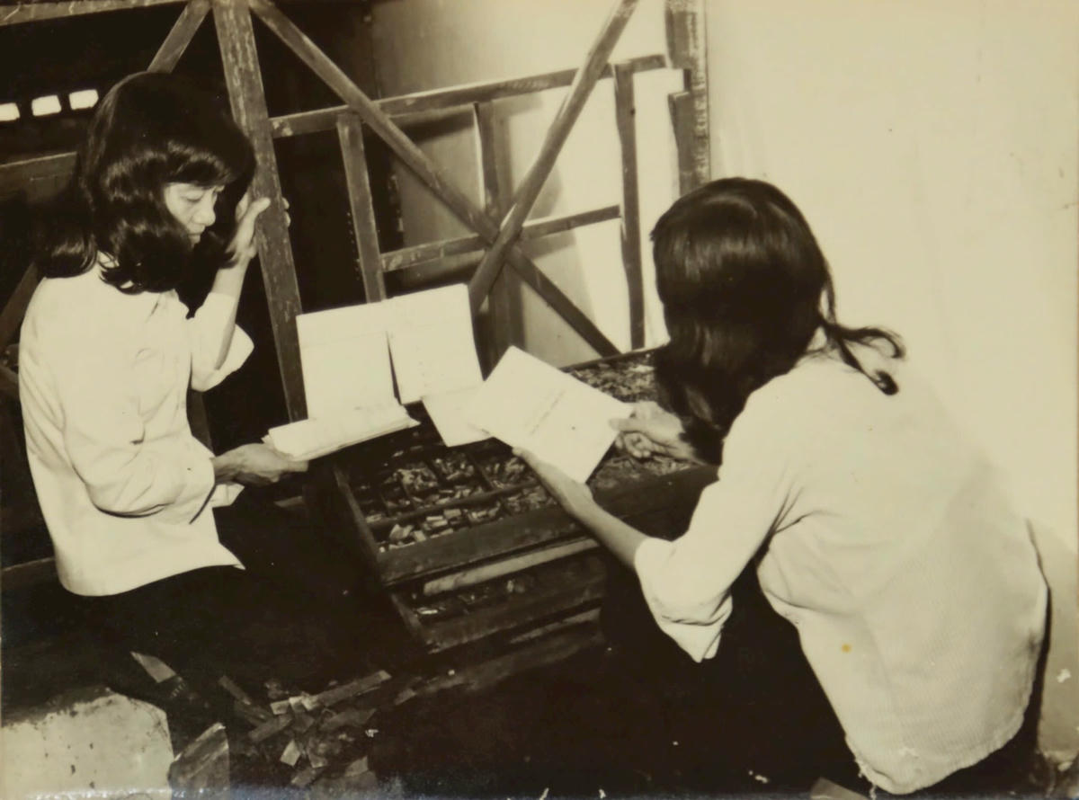 Bà Nguyễn Thị Ngọc Lành và bà Từ Thanh Mỹ (người ngồi quay lưng) bên bàn xếp chữ chì Nhà in Trí Thức Mới