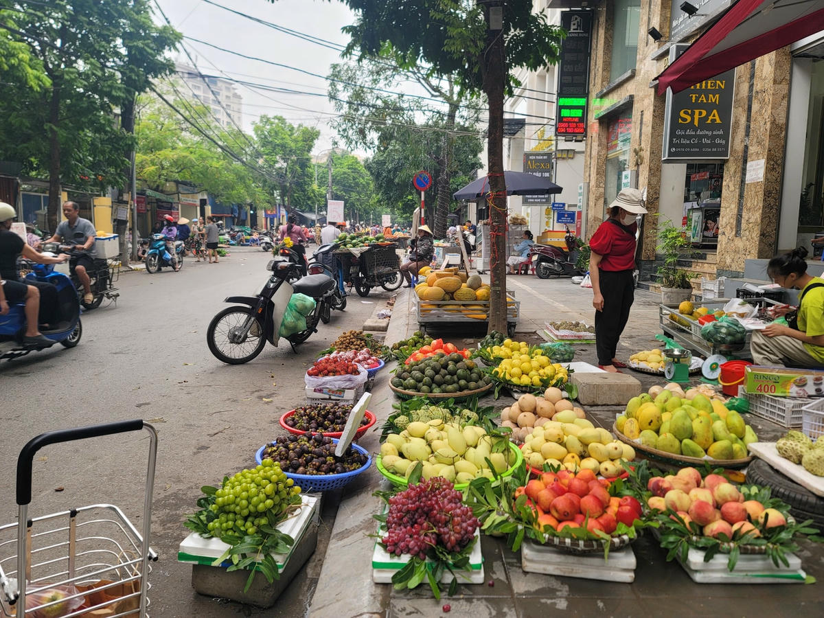 Nhiều cửa hàng hoa quả bày hàng bán tràn từ vỉa hè xuống lòng đường.