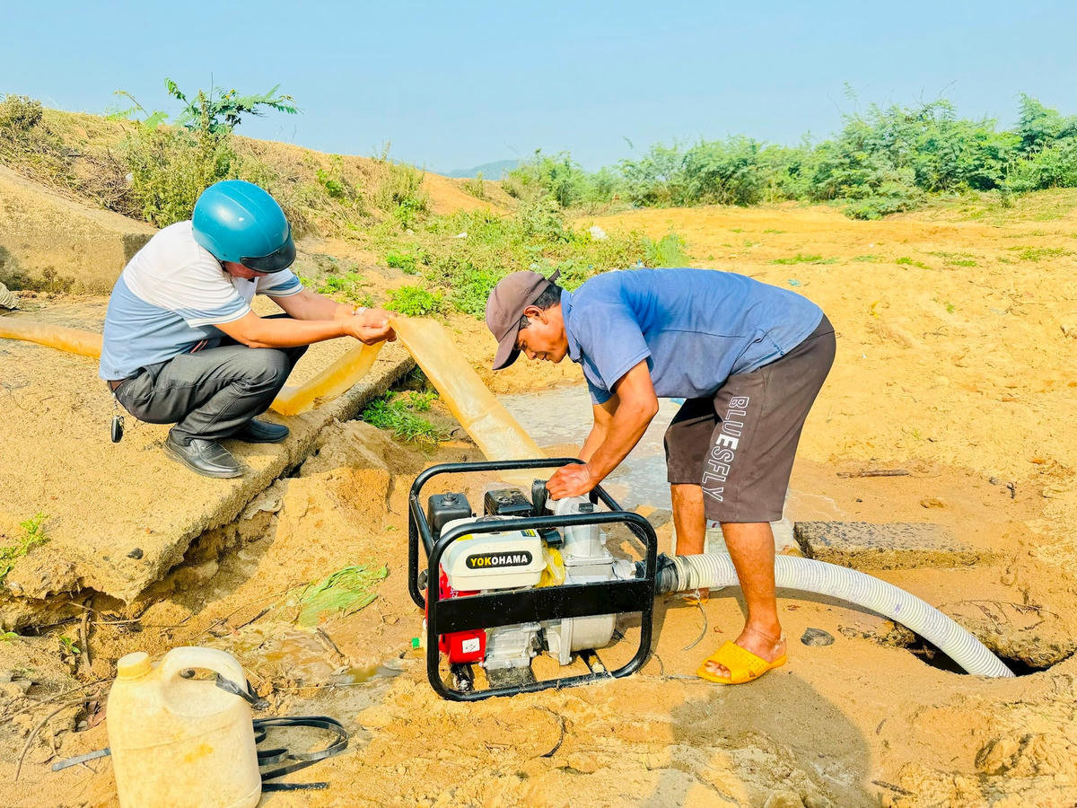 Ông Y KaPôk đang nối ống bơm nước ra ruộng.