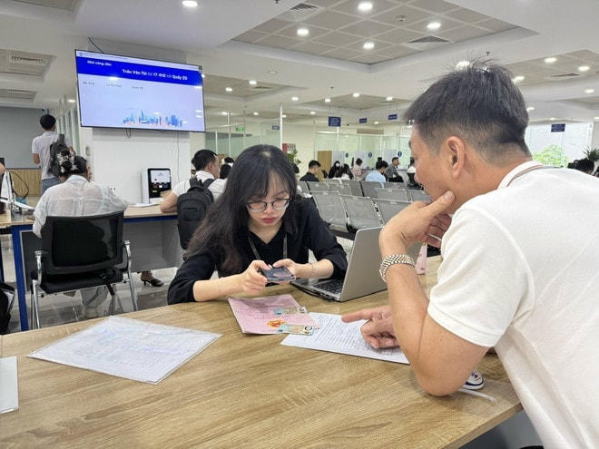 Cán bộ Trung tâm phục vụ hành chính công hướng dẫn người dân lấy số thứ tự online đối với hồ sơ liên quan đến đất đai qua ứng dụng iHanoi. (Ảnh: Quốc Lũy/TTXVN) vna-potal-ap-dung-ihanoi-khong-con-canh-nguoi-dan-xep-hang-lam-thu-tuc-dang-ky-dat-dai-8033650.jpg