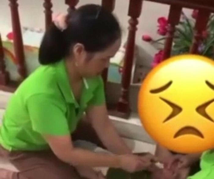 Hình ảnh 2 người đè cháu bé xuống sàn nhà đút cơm khiến dư luận bức xúc. Ảnh: VTC News.