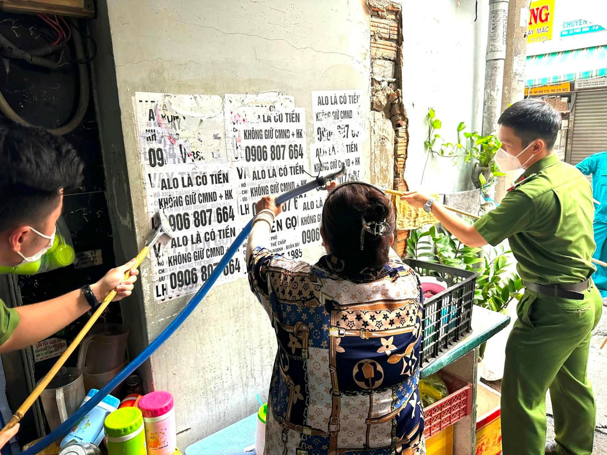 Công an quận Tân Bình, TP HCM hướng dẫn người dân tham gia tháo gỡ quảng cáo tín dụng đen bôi bẩn tại khu dân cư.