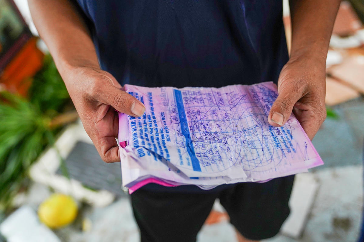 Cầm chặt cuốn sổ ghi nợ đã bị nước mưa làm nhòe mực, anh Đạo cố giữ lại thứ tài sản duy nhất còn sót lại. Ảnh: Cẩm Kỳ