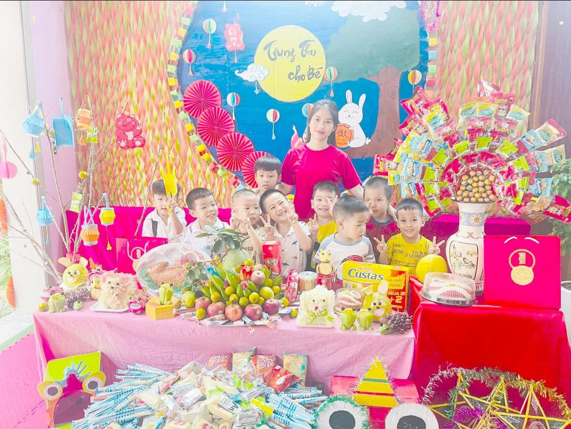 Các bạn nhỏ chụp ảnh cùng cô giáo bên mâm cỗ Trung thu ấm áp.