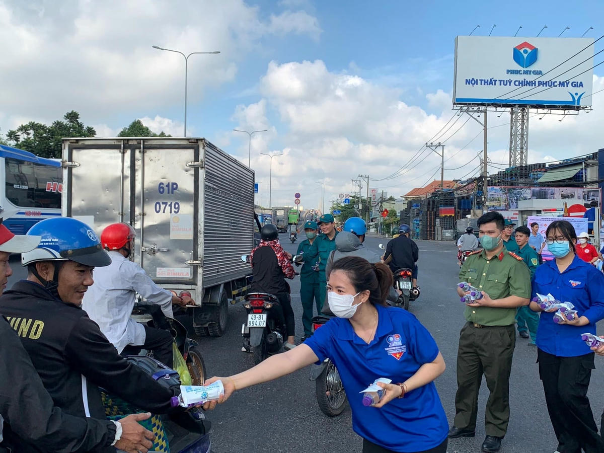 Vừa điều tiết giao thông, lực lượng tình nguyện viên tặng nước uống và khăn lạnh cho người đi đường trên Quốc lộ 1A, đoạn qua địa bàn TP Thủ Đức.