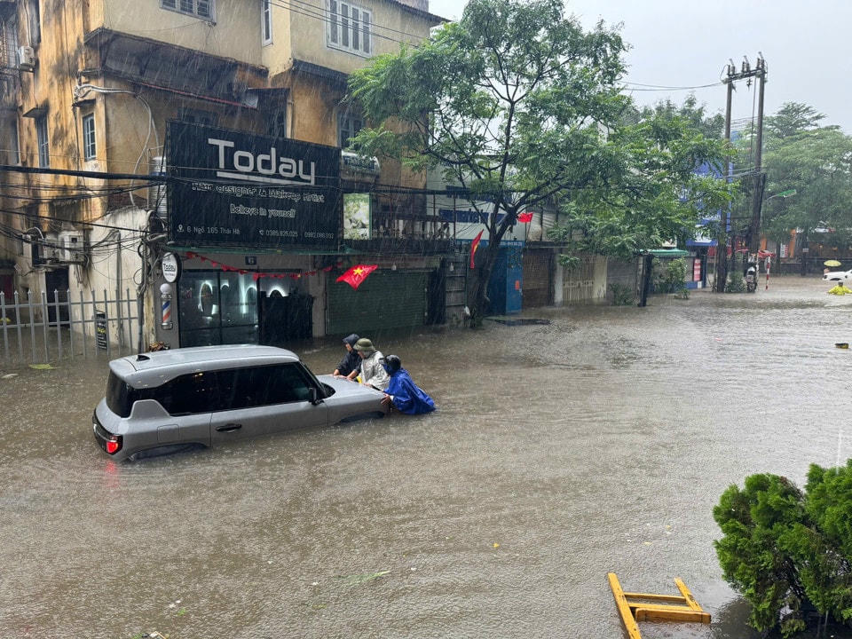 Người dân cố gắng đẩy phương tiện chết máy tới chỗ cao ráo hơn. (Ảnh: Hoài Nam/Vietnam+)