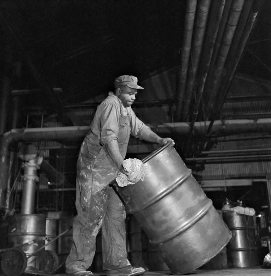 William B Wilson, thợ làm dầu, chuyển một thùng dầu nhớt. Ảnh: The Guardian.