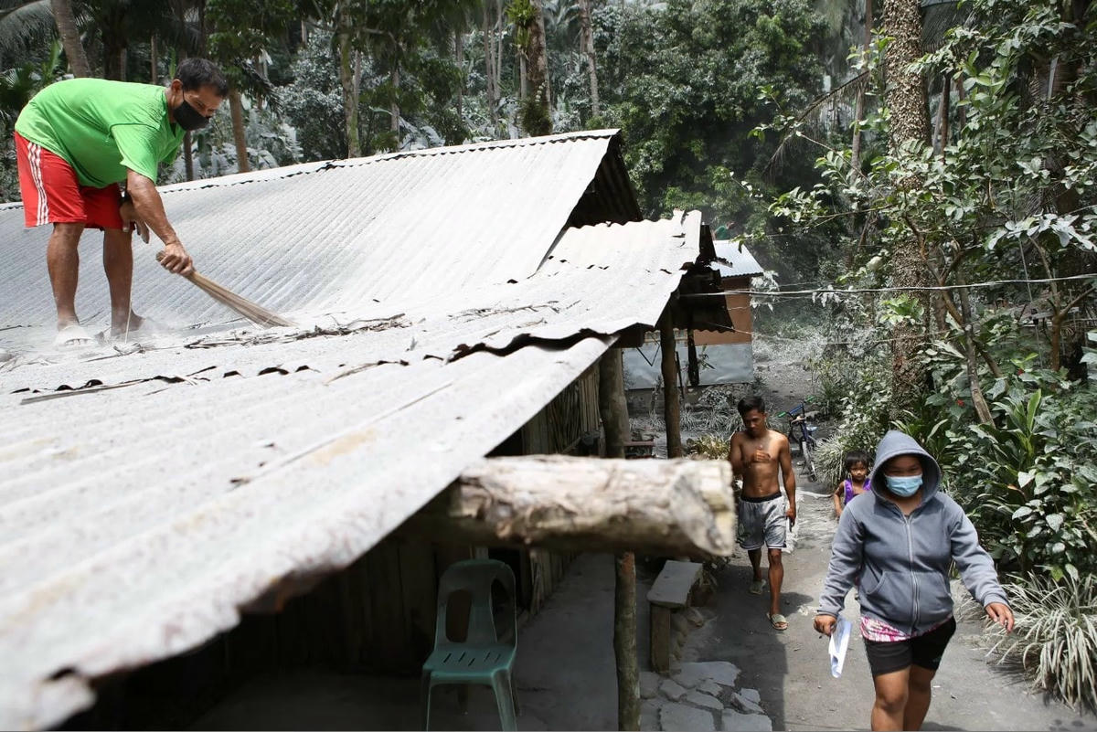 Một người dân quét sạch tro bụi trên mái nhà của mình. Ảnh: Getty Images.