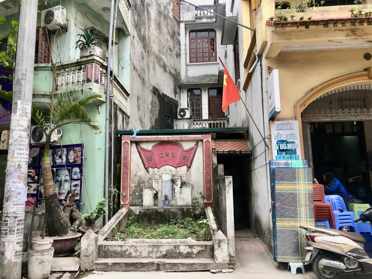 Ngôi mộ nằm ngay phía trước mặt tiền của một ngôi nhà 3 tầng. Thậm chí cổng chính ngôi nhà còn hẹp hơn chiều ngang ngôi mộ.