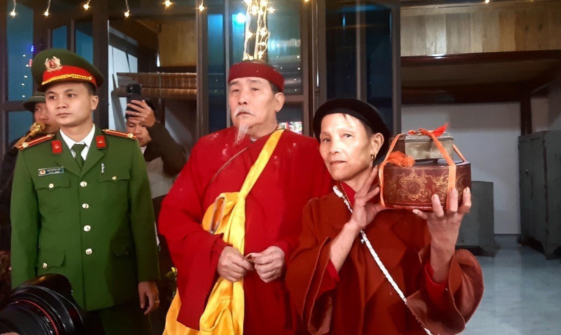 Quá trình di chuyển, lực lượng công an, biên phòng luôn đi bên cạnh bà Nguyễn Thị Liên (58 tuổi, vợ tân cố đạo chủ) để làm nhiệm vụ bảo vệ, giữ trật tự. Bà Liên đang cầm trên tay chiếc hộp đựng những báu vật.