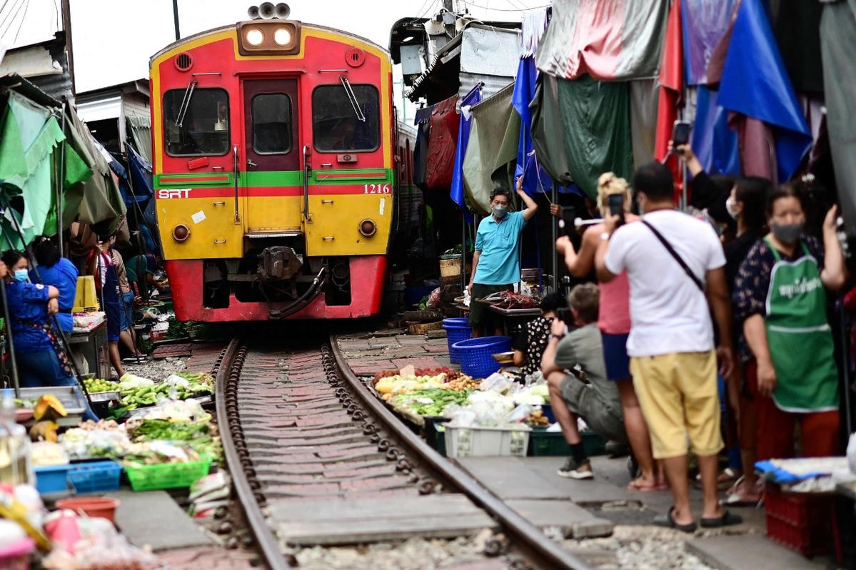 Người bán hàng và du khách đứng chờ khi đoàn tàu đi qua Chợ đường tàu Mae Klong ở tỉnh Samut Songkhram. Ảnh: AFP.