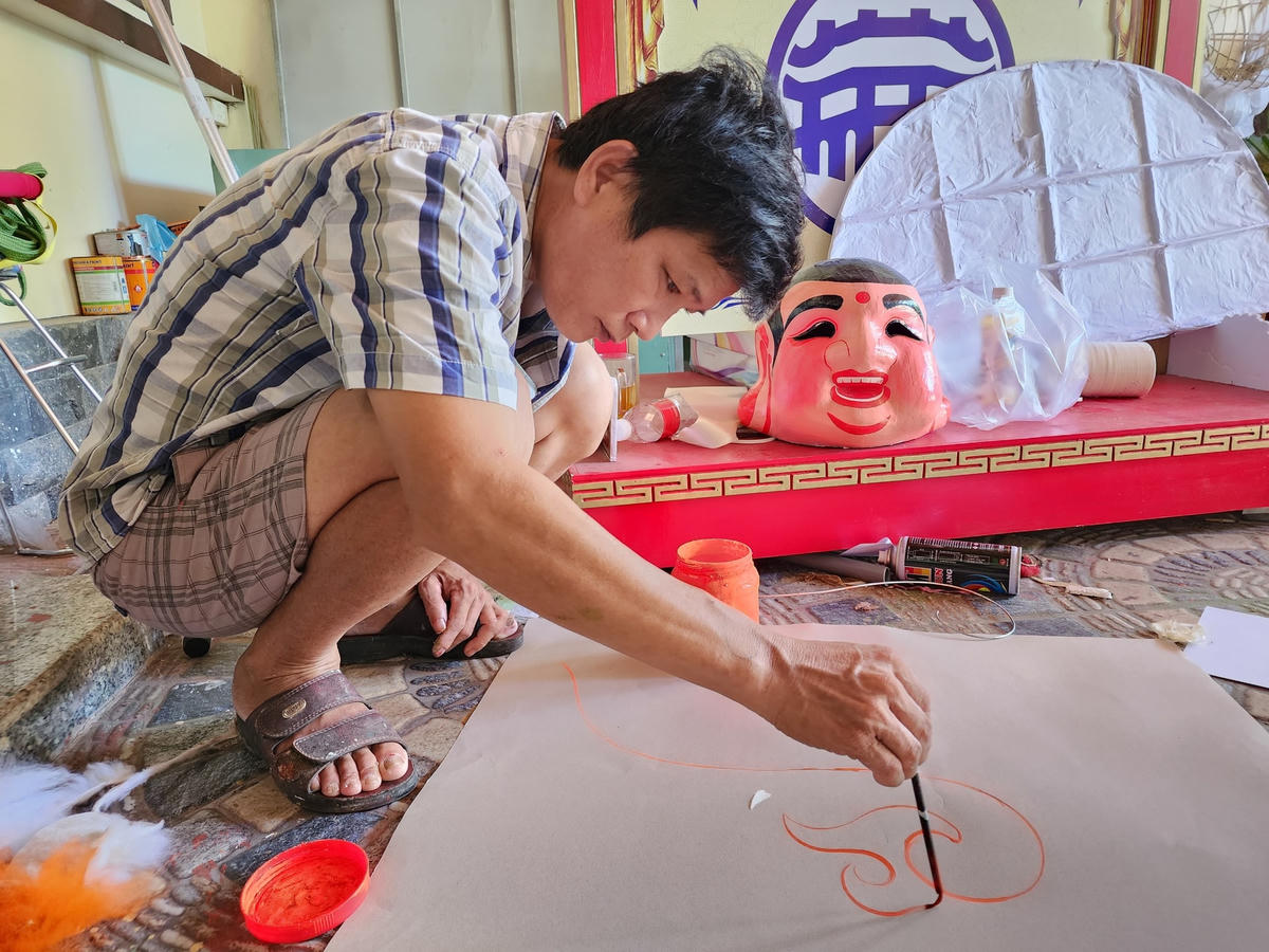 Vẽ nét hoa văn trên giấy trước khi dán vào đầu Lân.