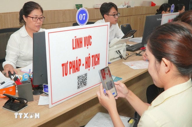 Người dân quét mã QR để tra cứu thủ tục và quy trình hồ sơ thuộc lĩnh vực tư pháp-hộ tịch. (Ảnh: Hữu Duyên/TTXVN) ttxvn-chinh-quyen-dia-phuong-hai-cap-thanh-pho-ho-chi-minh-2.jpg