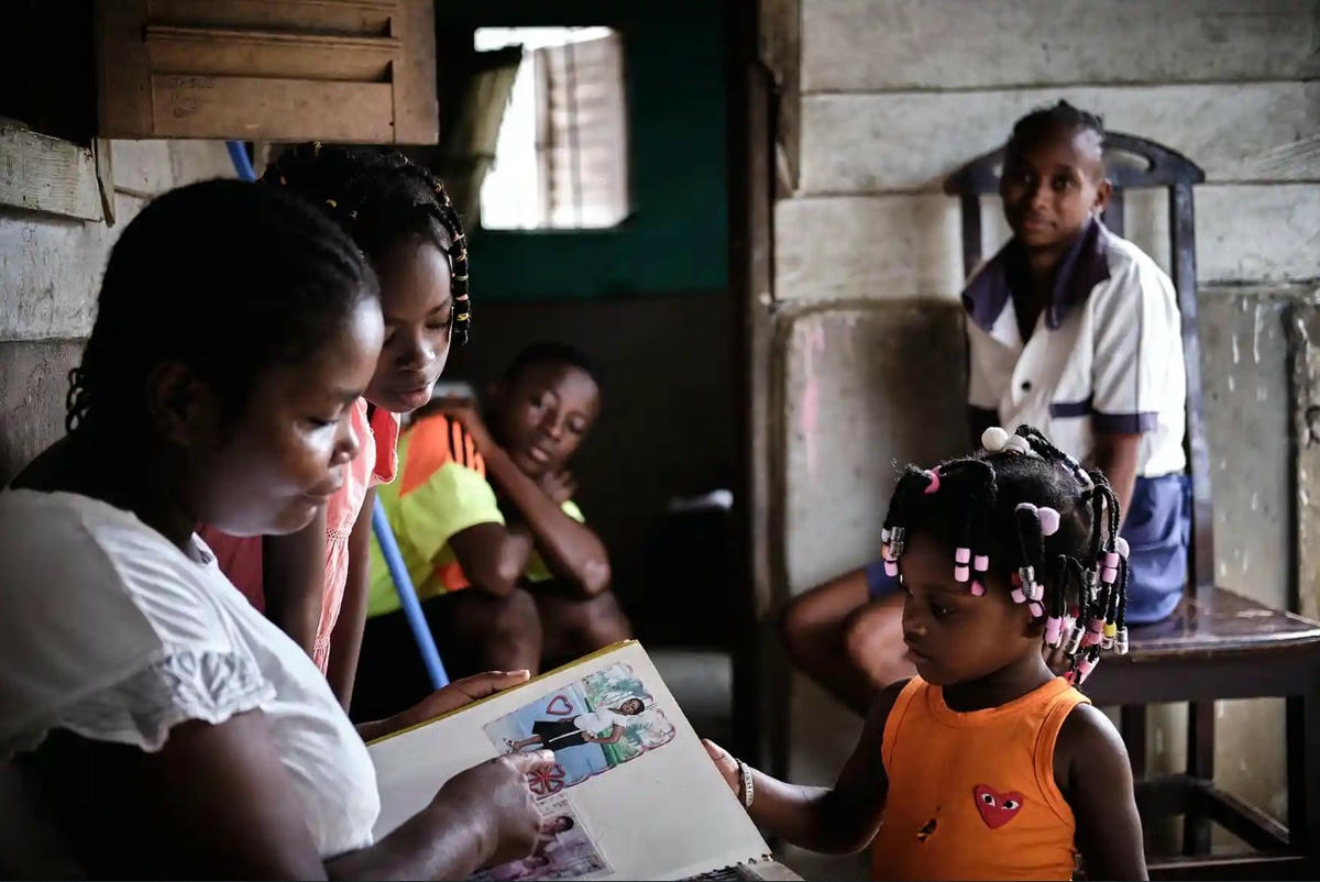 Bilogo, trong sân của ngôi nhà của cô, cho các con và hàng xóm xem một bức ảnh của cô. Ảnh: Diego Menjibar Reynes.