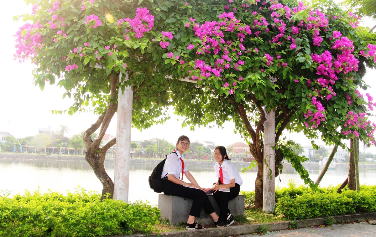 Các em học sinh bên bờ hồ Nguyễn Du khi hoa giấy đang khoe sắc.