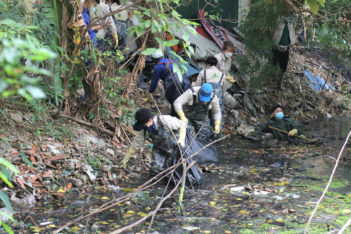 A3: Tình nguyện viên ngâm mình hàng giờ dưới dòng nước đen ngòm đầy rác thải.