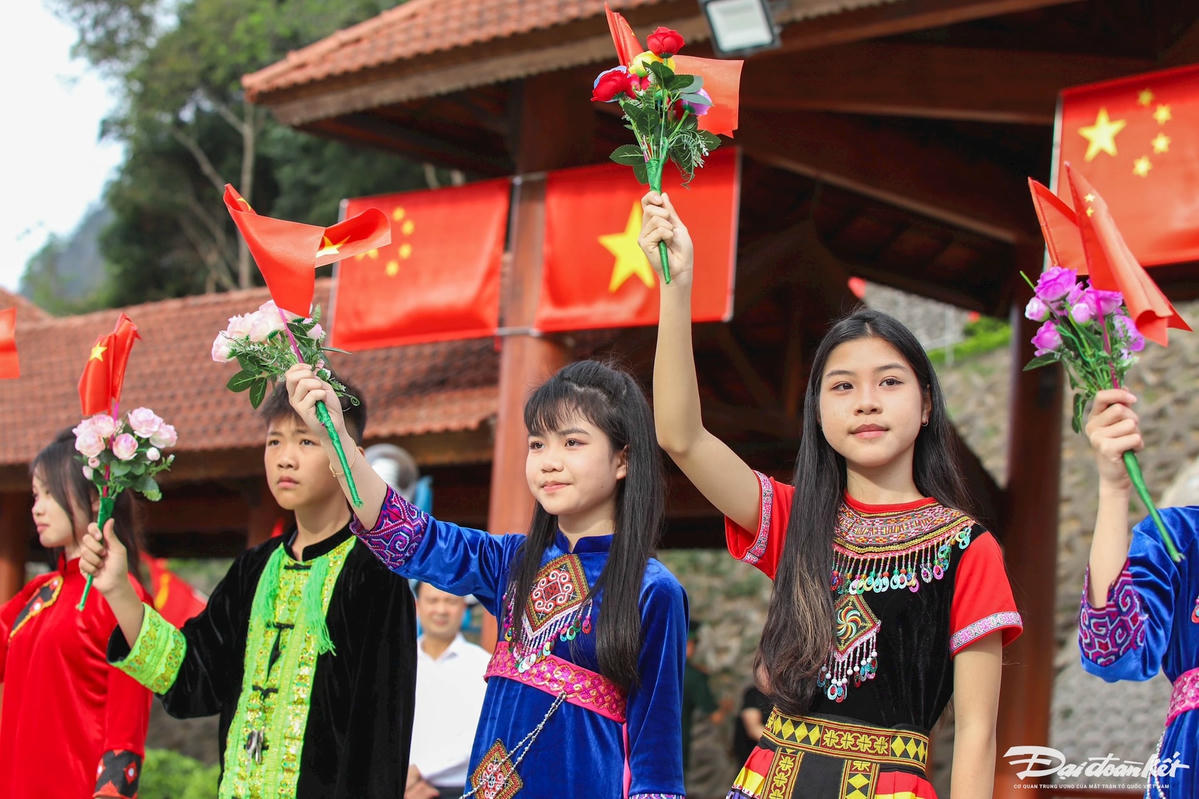 Các em học sinh vẫy cờ hoa chào đón đoàn đại biểu cấp cao Mặt trận Tổ quốc Việt Nam. Ảnh: Quang Vinh