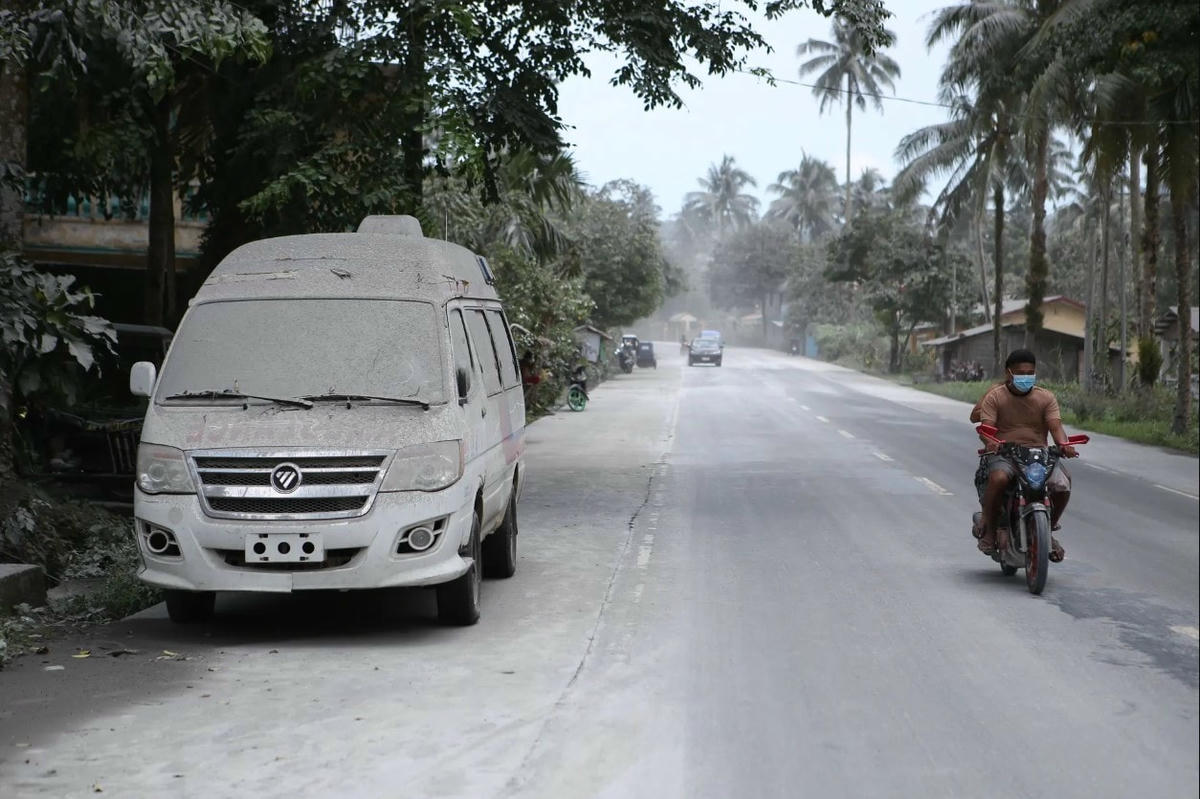 Một người đi xe máy đi qua chiếc xe cấp cứu phủ đầy tro bụi. Ảnh: Getty Images.