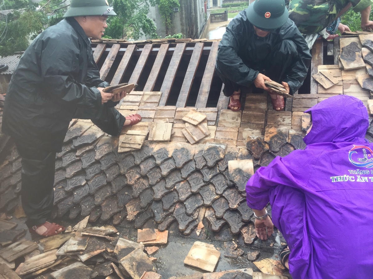 Lực lượng chức năng, chính quyền đoàn thể giúp dân lợp lại mái nhà.