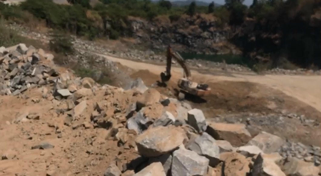 Xe múc hoạt động bên dưới hố khai thác đá