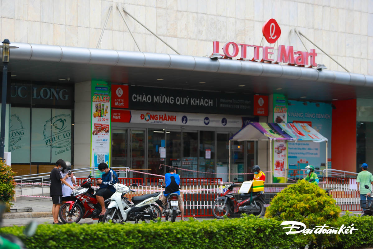 Rất đông người đội nắng chờ người thân mình đi siêu thị mua hang.