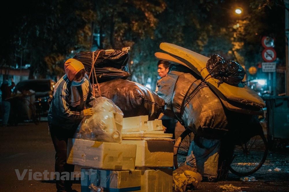 Đã gần 1 giờ sáng, vợ chồng anh T vẫn hì hục phân chia đồ nhựa, giấy rác, sắt vụn tại con phố Phủ Doãn. Anh chia sẻ: “Tôi xin rác ở các bệnh viện rồi phân loại ra để bán đồng nát. Dù không được một số tiền lớn nhưng nó có thể giúp tôi trang trải cuộc sống hằng ngày.” (Ảnh: Minh Hiếu/Vietnam+).