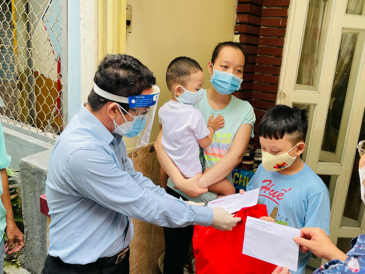 Nhà báo Chu Ninh, Trưởng Ban đại diện Báo Đại Đoàn kết tại TP HCM trao quà tặng cháu Bùi Nhật Quang Đăng. Ảnh: Hữu Vinh.