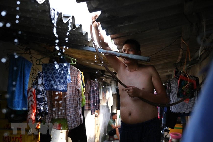 Trước cái nóng như rang, người lao động ở xóm trọ Phúc Xá phải phun nước liên tục lên mái nhà để giảm nhiệt. (Ảnh: Thành Đạt/TTXVN).