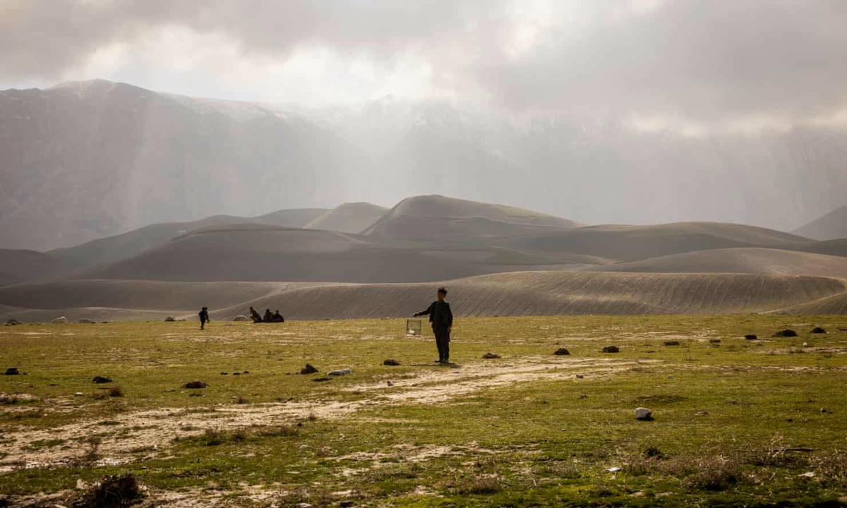 Một cậu bé đứng trong một trại di dời ở tỉnh Balkh, nơi các gia đình phải đào chỗ ở dưới lòng đất để sưởi ấm qua mùa đông. Ảnh: The Guardian.