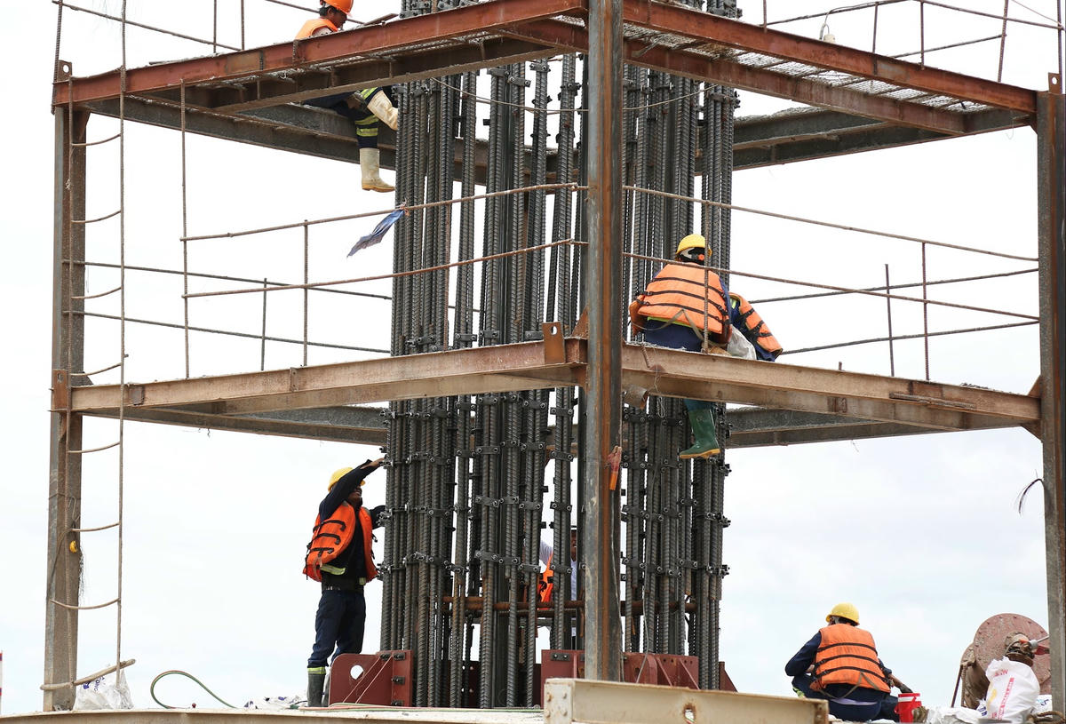 Các công nhân đang thi công trụ cầu giữa sông.