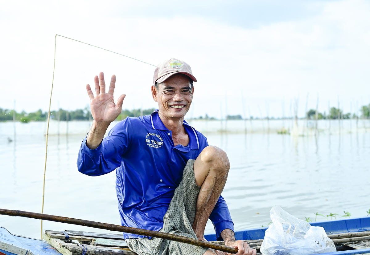 Một người dân mưu sinh trên đồng nước nổi vui mừng, vẫy tay chào cán bộ, chiến sĩ đồn biên phòng Vĩnh Nguơn sau khi được ghé thăm, hỏi han đời sống. Ảnh Nguyễn Minh. 