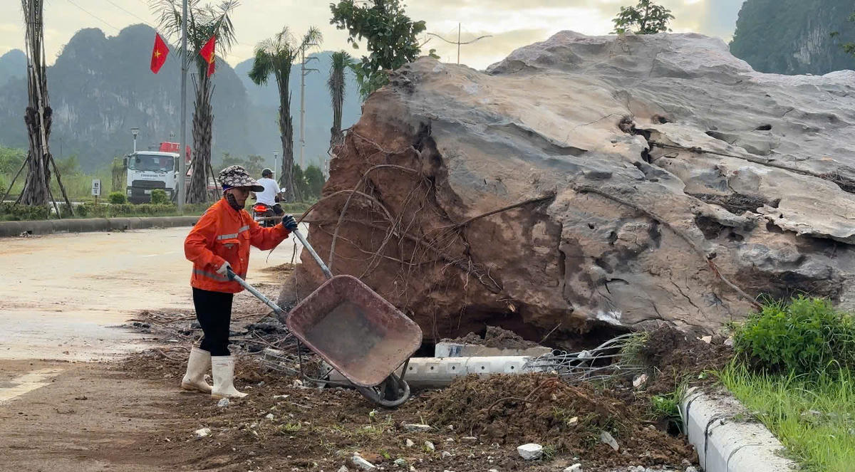 Công nhân xúc hót đất đá rơi vãi ra đường để không gây cản trở phương tiện lưu thông. Ảnh: Ngọc Anh.