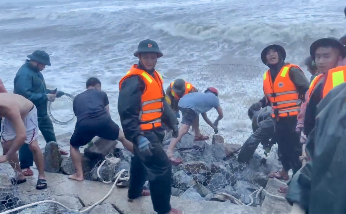 Lực lượng chức năng cùng người dân bốc từng khối đá, buộc dây thép, lấp rọ tạo thành hàng rào tạm thời giữ lại phần kè còn lại.