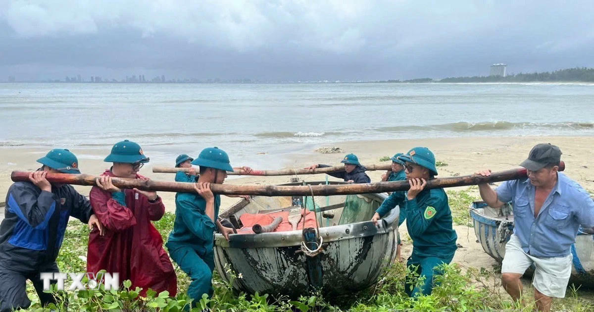 Lực lượng chức năng phường Hải Vân giúp ngư dân đưa thuyền thúng lên bờ tránh bão. (Ảnh: TTXVN phát).