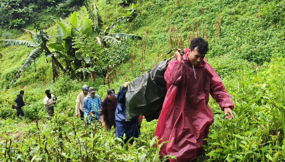 Lực lượng chức năng xã Hùng Sơn vượt đường núi hỗ trợ đưa bệnh nhân Lào về bản. Ảnh: Parai. 