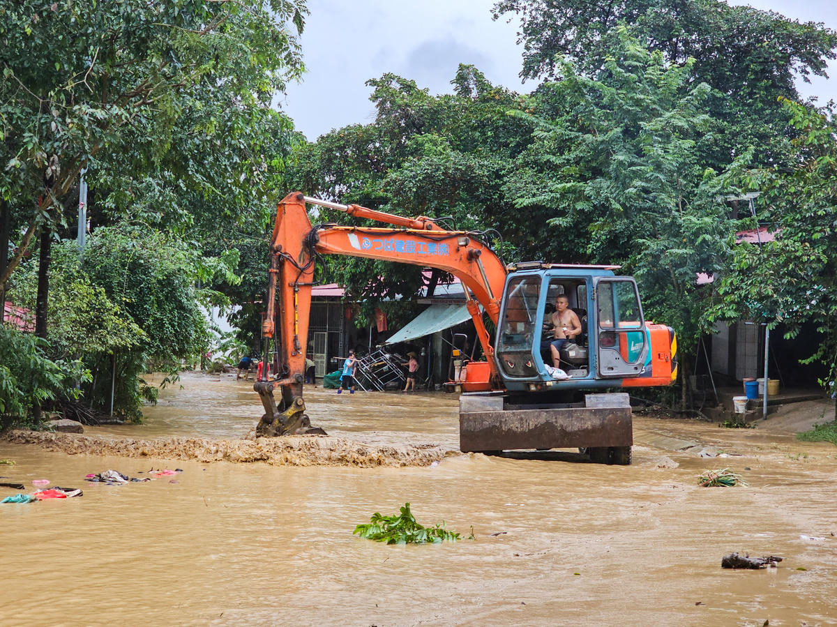 Ngoài ra, máy xúc, máy ủi cũng được huy động để dọn lượng đất phù sa đọng lại trong sân nhà và trên mặt đường. Ảnh: Đình Minh