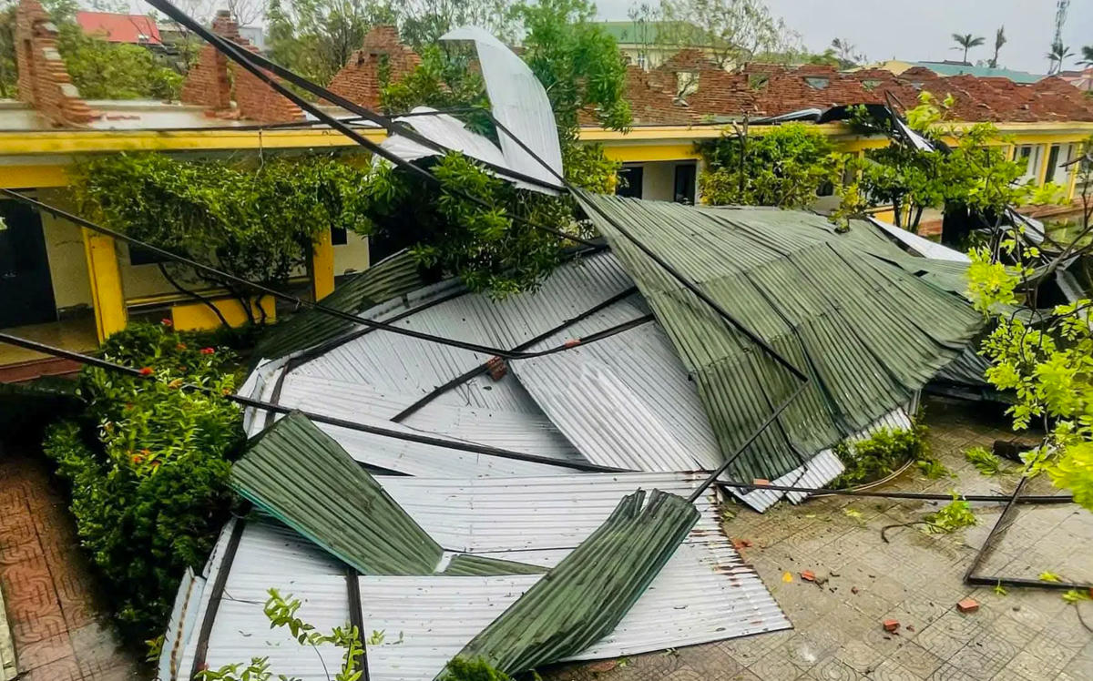 Mái tôn bị cuốn sập, che kín sân trường, khiến việc dạy học phải tạm dừng để khắc phục. Ảnh: Cẩm Kỳ.